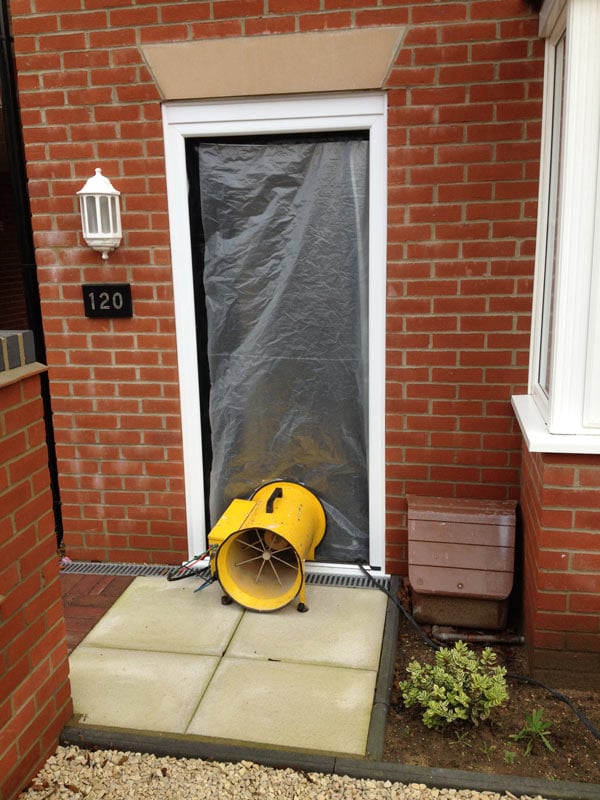 Air leakage testing equipment in sealed off doorway of house